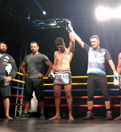 Kevem com o braço erguido no ringue de muay thai