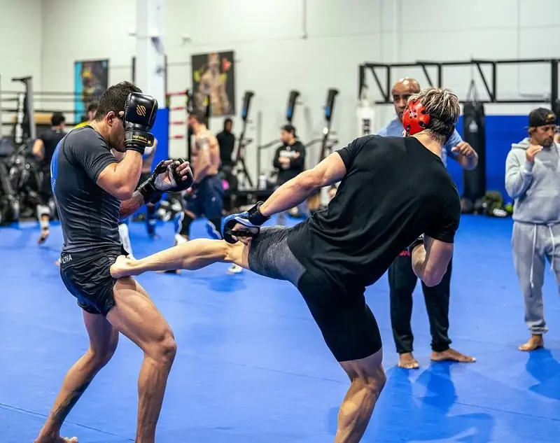 Kevem drills a kick with a partner on the mats